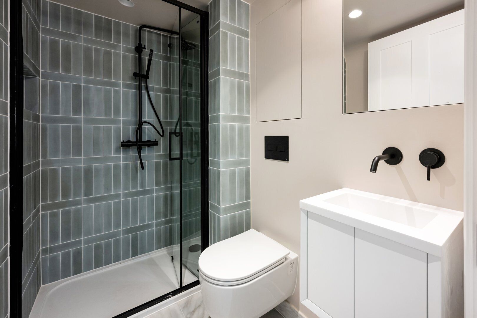 A modern bathroom with a glass shower enclosure, a white toilet, and a white sink with a cabinet.