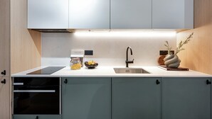 Eine moderne Küche mit Einbauofen, Spüle aus Edelstahl und einer dekorativen Vase auf der Arbeitsfläche.