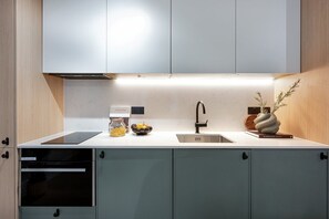 A modern kitchen with a built-in oven, a stainless steel sink, and a decorative vase on the countertop. - Normandy Court 1 (London)