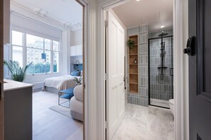 A modern bedroom with a large window, a bedside table, and a bed. - Cosy Studio Near Kensington Gardens (London)