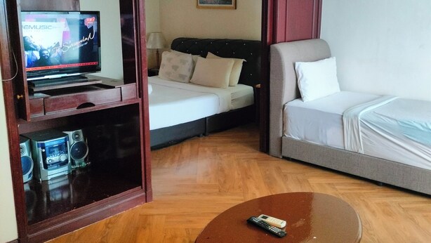 Quarto de hotel com cama, sofá, televisão e mesa de centro.