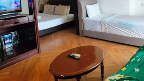 Quarto de hotel com cama, sofá, televisão e uma pequena mesa.