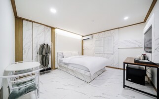 Habitación de hotel moderna con cama, escritorio, silla y zapatero.