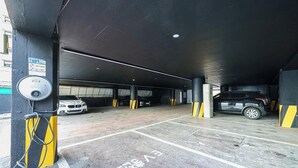 An underground parking garage with multiple parking spaces, a security camera, and a charging station. - Hasen Wolgot Hotel (Siheung)