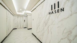 A hallway with marble walls and floor, leading to a door labeled "HASEN". - Hasen Wolgot Hotel (Siheung)