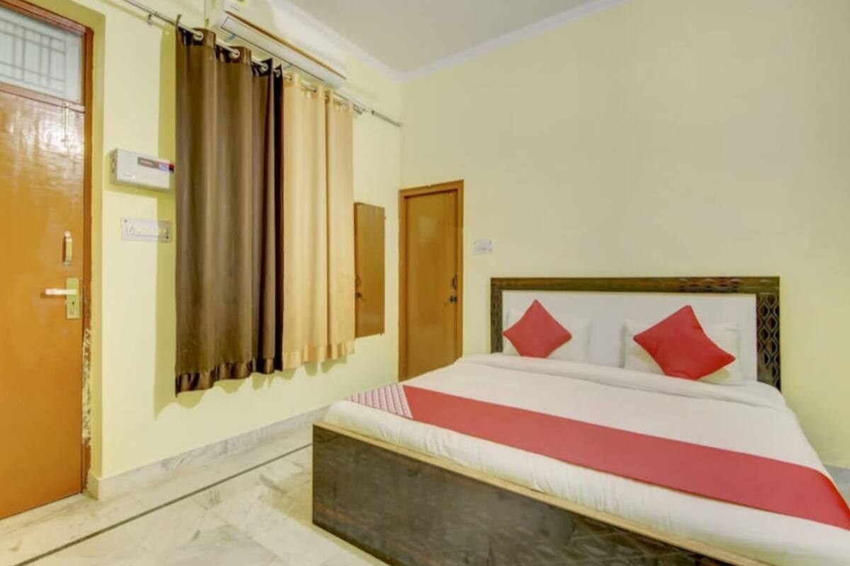 Une chambre à coucher avec un lit, des rideaux, une porte en bois et un climatiseur fixé au mur.