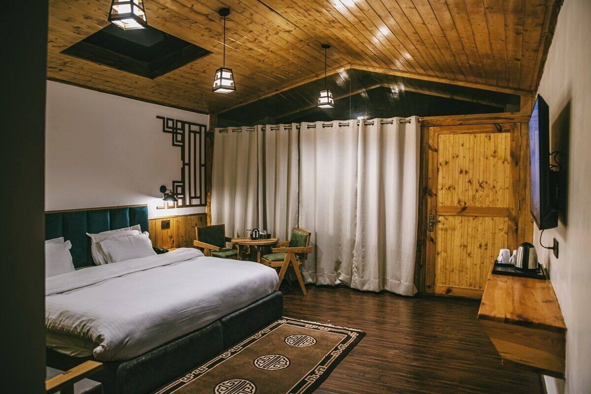 Ein Schlafzimmer mit einem großen Bett, Holzboden und einem kleinen Tisch mit Stühlen.