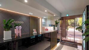 A hotel reception area with a modern design, featuring a reception desk, a wall-mounted sign, and a glass door leading outside. - Gwangmyeong Hotel Levento (Gwangmyeong)