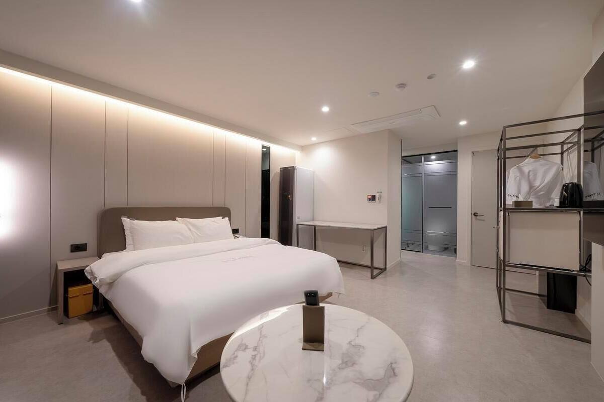 Een moderne hotelkamer met een groot bed, een nachtkastje, een bureau en een kledingkast met ophanging.