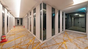 A long corridor with mirrored walls, a patterned carpet, and fire extinguishers. - Gwangmyeong Hotel Levento (Gwangmyeong)