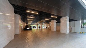 A spacious indoor parking area with a modern design, featuring a grid-patterned ceiling and large pillars. - Gwangmyeong Hotel Levento (Gwangmyeong)