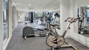 A gym with cardio machines, weight machines, and a mirrored wall. - Room-room in Melbourne CBD (Melbourne)