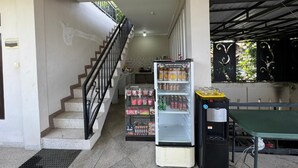 Uno spazio commerciale con una scala, una vetrina refrigerata e un tavolo con un distributore d'acqua.
