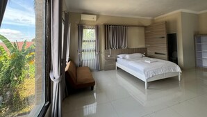 Camera d'albergo moderna con un letto grande, un'area salotto e vista sull'esterno.