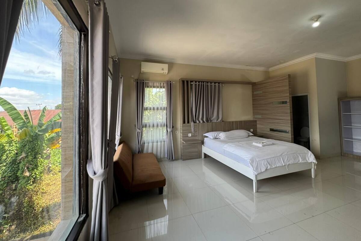 A modern hotel room with a large bed, a seating area, and a view of the outdoors.