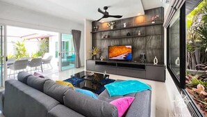 Ein modernes Wohnzimmer mit grauem Sofa, Flachbildfernseher und Deckenventilator.
