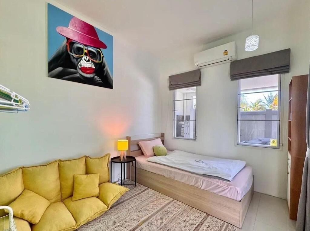 Un dormitorio con cama, sofá, lámpara y un cuadro en la pared.