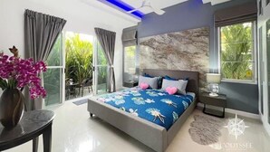 Ein modernes Schlafzimmer mit einem großen Bett, einem Deckenventilator und Blick ins Grüne.