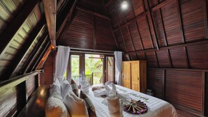 Una habitación de madera con una cama, un banco y un ventanal.