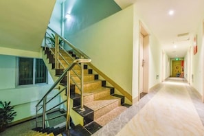 A staircase with a metal handrail leading to a landing. A hallway extends from the landing with a light-colored floor. - Xiamen qing cha Hotel (Xiamen)