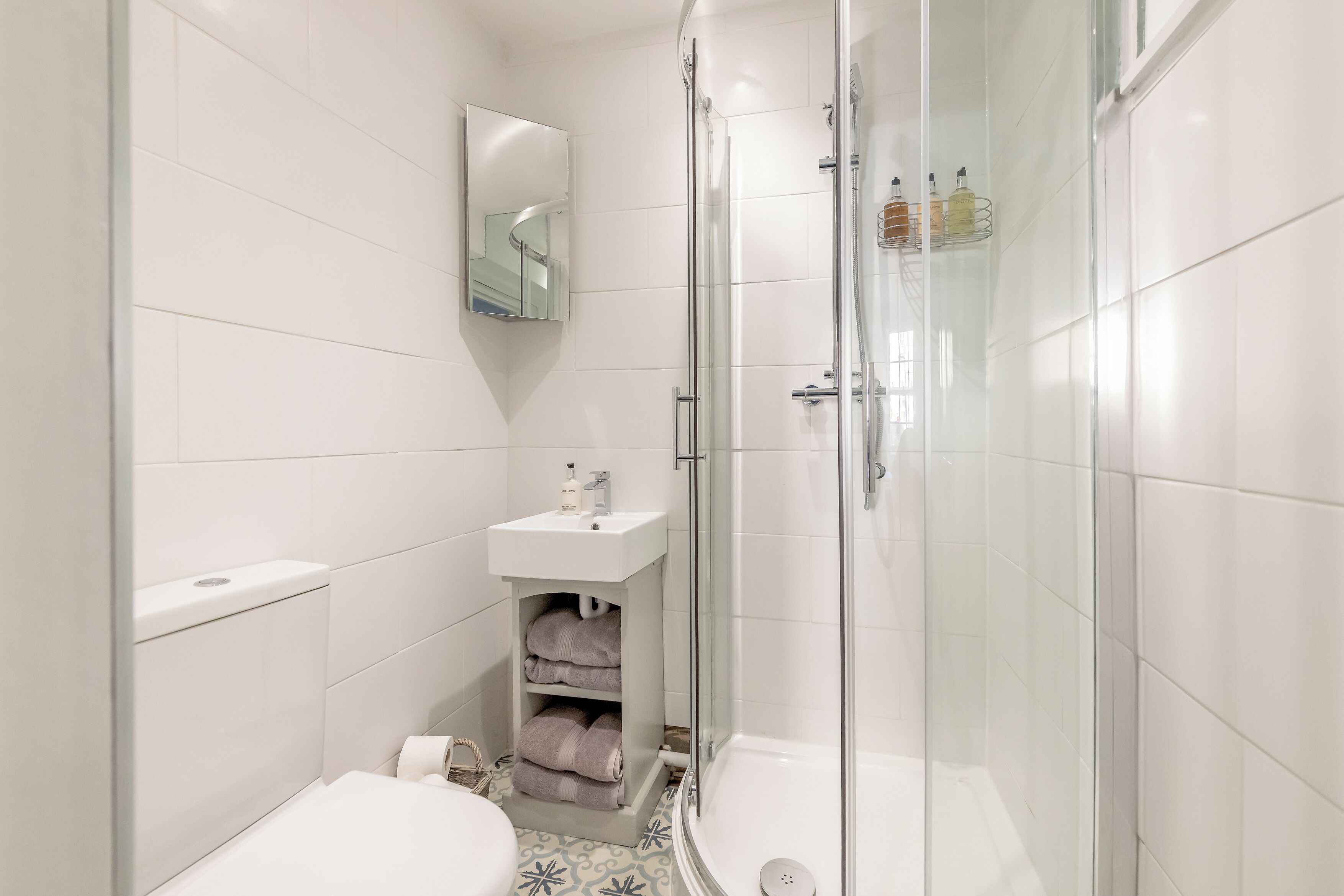 Et moderne badeværelse med toilet, håndvask og brusekabine med glasvægge.
