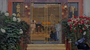 The entrance of Grand Villa with a glass door, steps, and a red and white flower arrangement. - Hotel Grande Villa Near Delhi Airport (New Delhi)
