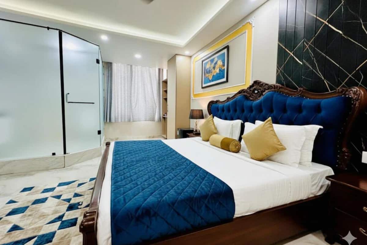 A hotel room with a large bed, a wardrobe, a nightstand, and a painting on the wall.