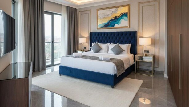 A modern hotel room with a large bed, a flat-screen TV, a desk, and a view of the city. - Hotel Grande Villa Near Delhi Airport (New Delhi)