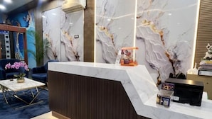 A reception area with a marble counter, wooden paneling, and a decorative wall. - Hotel Grande Villa Near Delhi Airport (New Delhi)