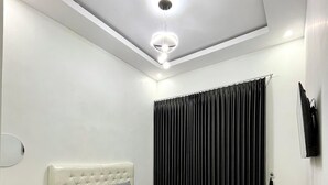 A bedroom with a bed, a bedside table, a TV, and a ceiling light fixture. - Lovia Villa Dieng (Kejajar)