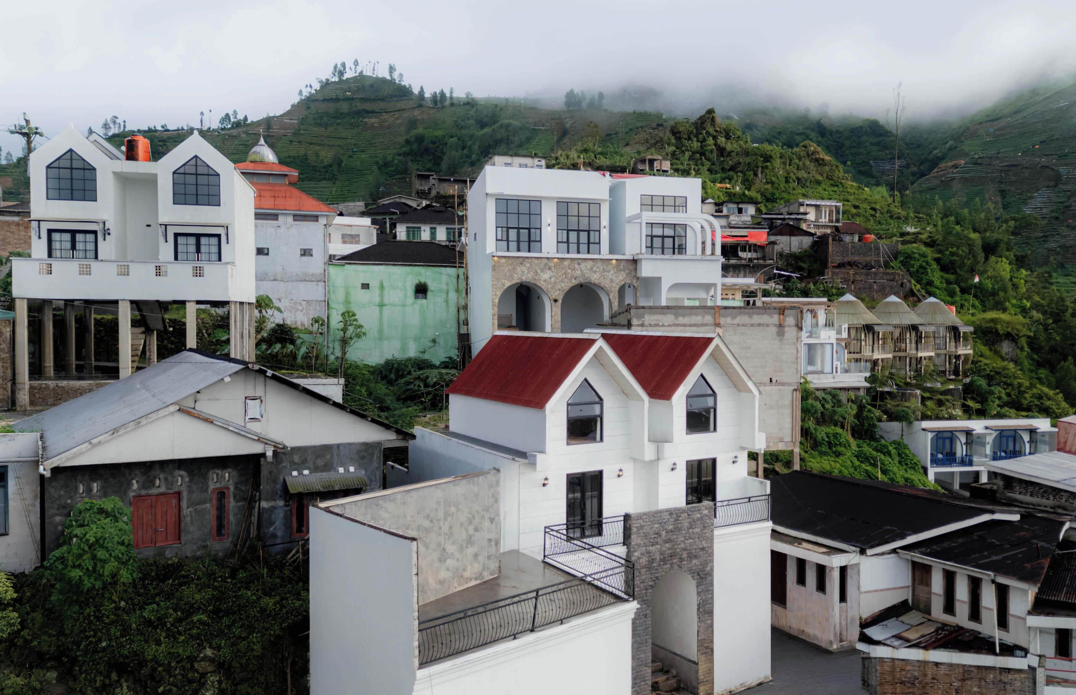 A residential area with various buildings, including houses with different roof styles and colors, and a prominent white building with a stone facade.