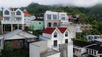 A residential area with various buildings, including houses with different roof styles and colors, and a prominent white building with a stone facade.
