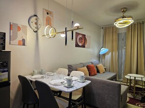 Una habitación de hotel moderna con zona de comedor, sofá y ventilador de techo.