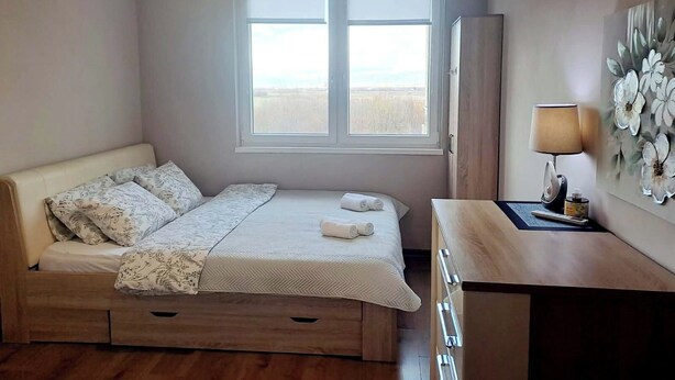 Un dormitorio con cama, escritorio, lámpara y ventana con vistas.