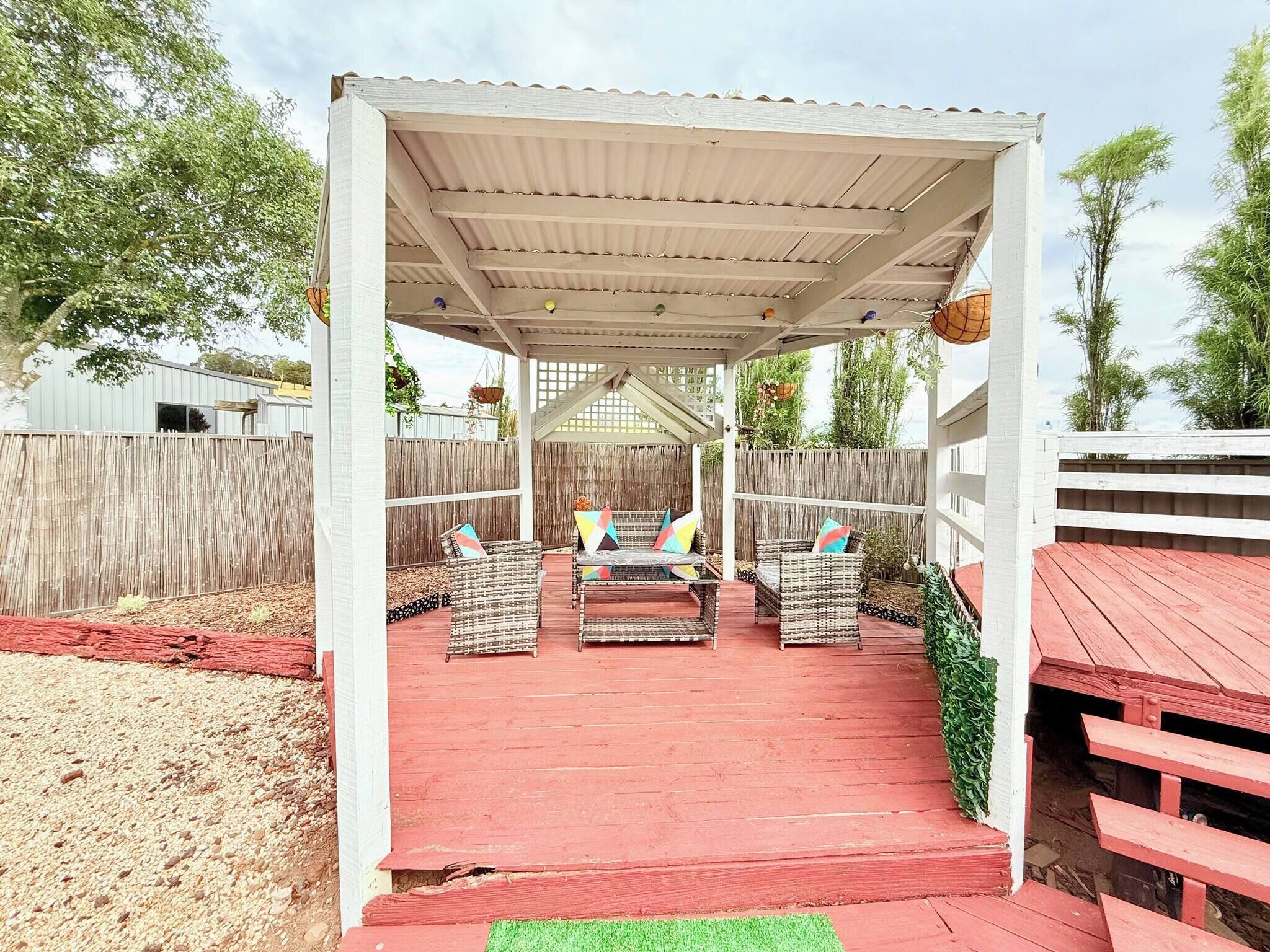A covered patio area with wicker furniture and a red floor.