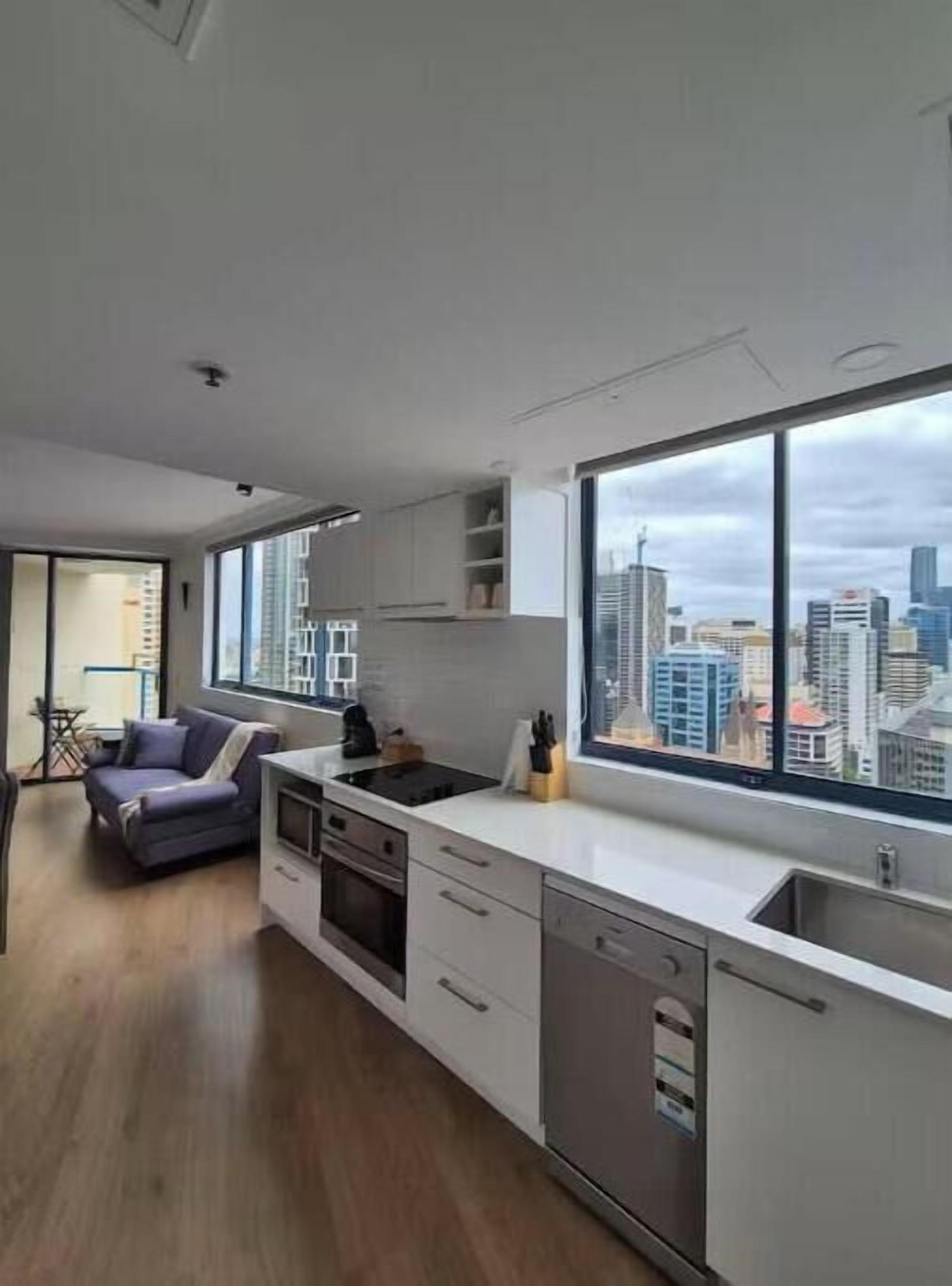A modern kitchen with a large window, white cabinetry, and a built-in oven.