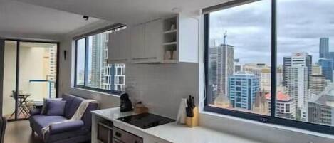 A modern kitchen with a large window, white cabinetry, and a built-in oven.