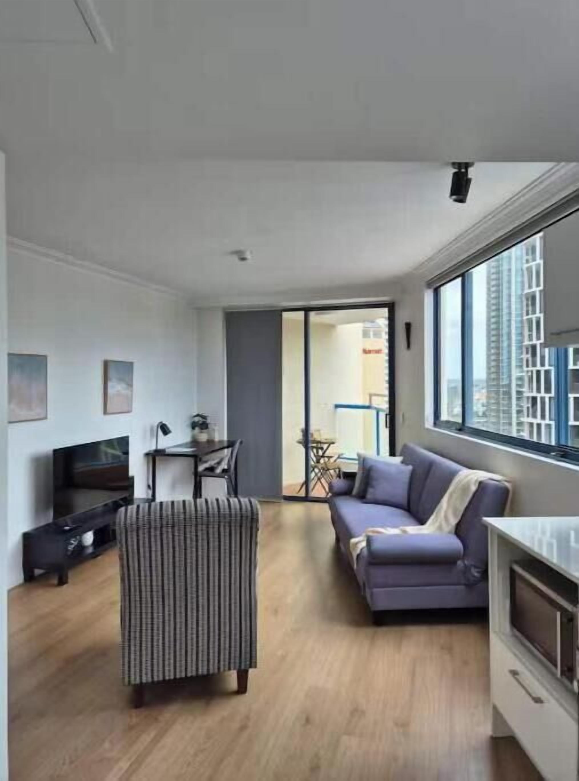 Un salon moderne avec un canapé, un fauteuil à rayures, un téléviseur et un coin repas comprenant une table et des chaises.