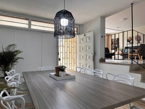 A dining area with a long wooden table, white chairs, a hanging black pendant light, and a potted plant. - Group stay 21 guests,  WiFi 900 Mb (Medellín)