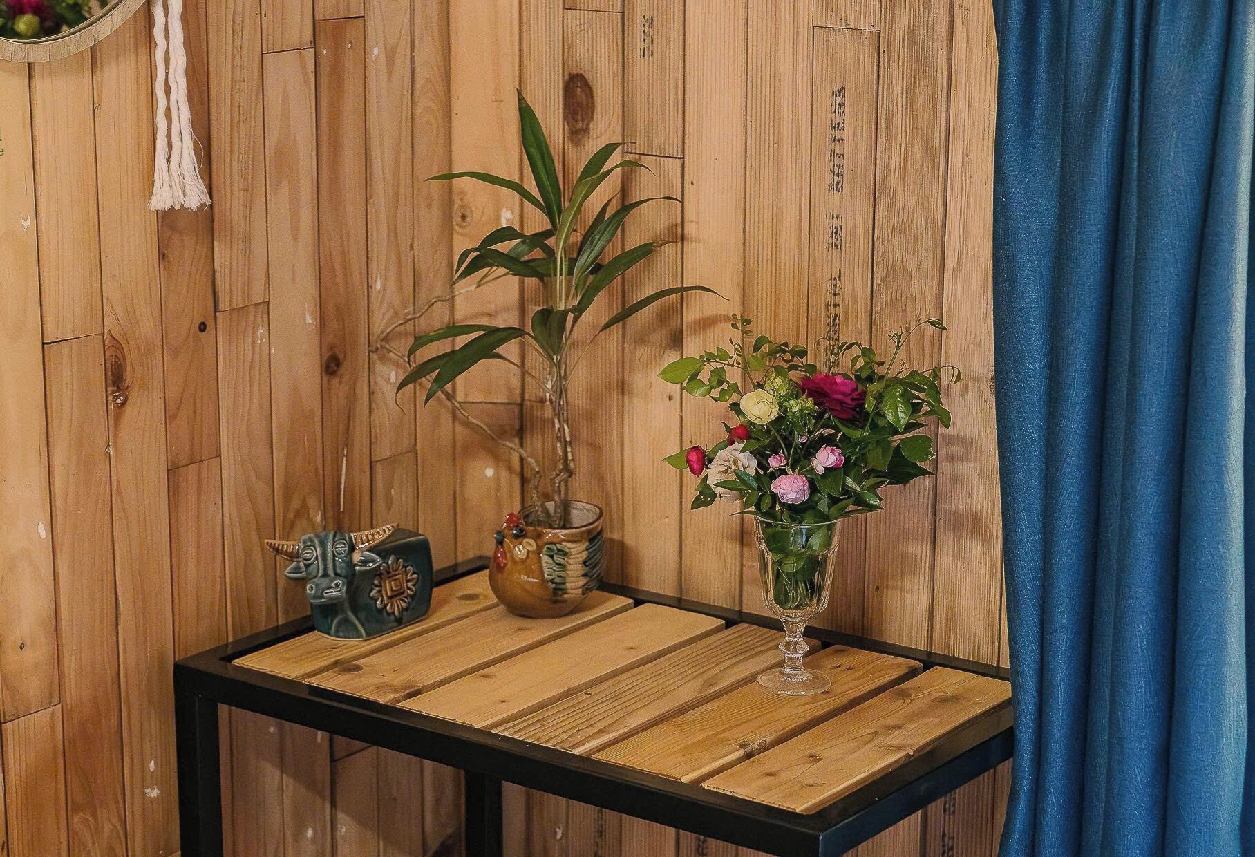 A wooden wall with a bamboo plant and a vase of flowers on a table.