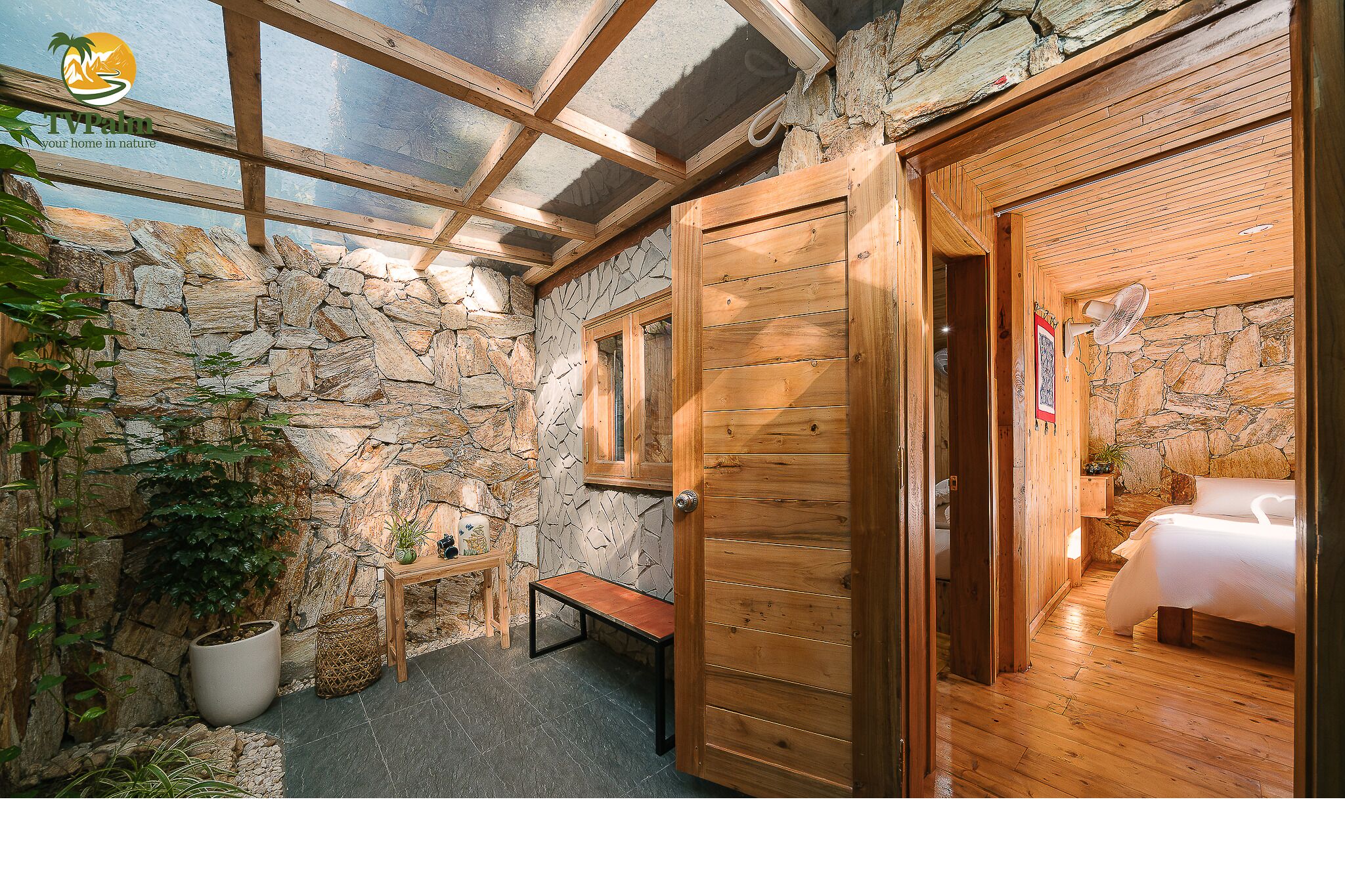 A wooden room with a stone wall, a bench, and a bed.