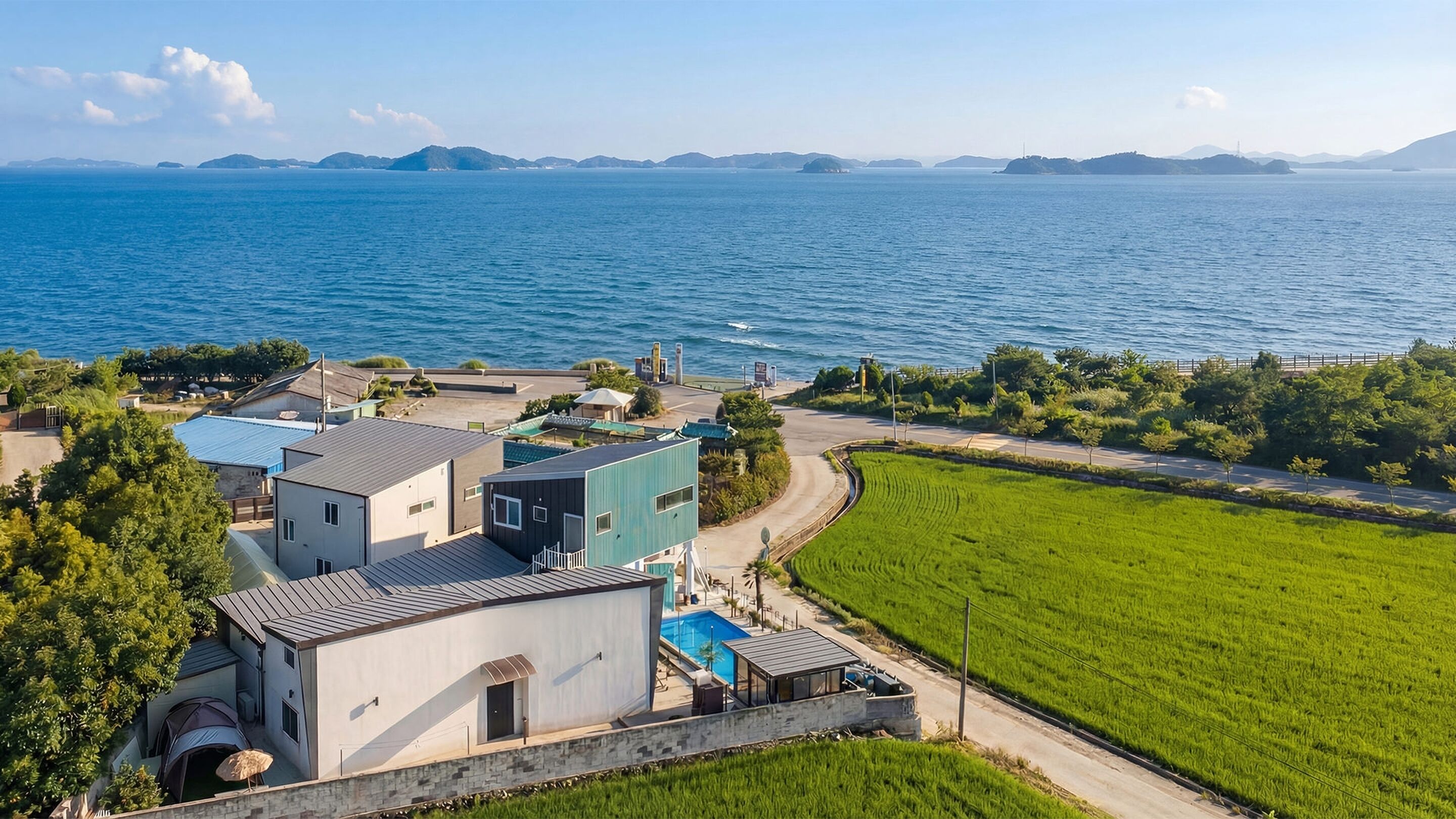 A coastal property with a swimming pool, a tennis court, and a view of the sea.