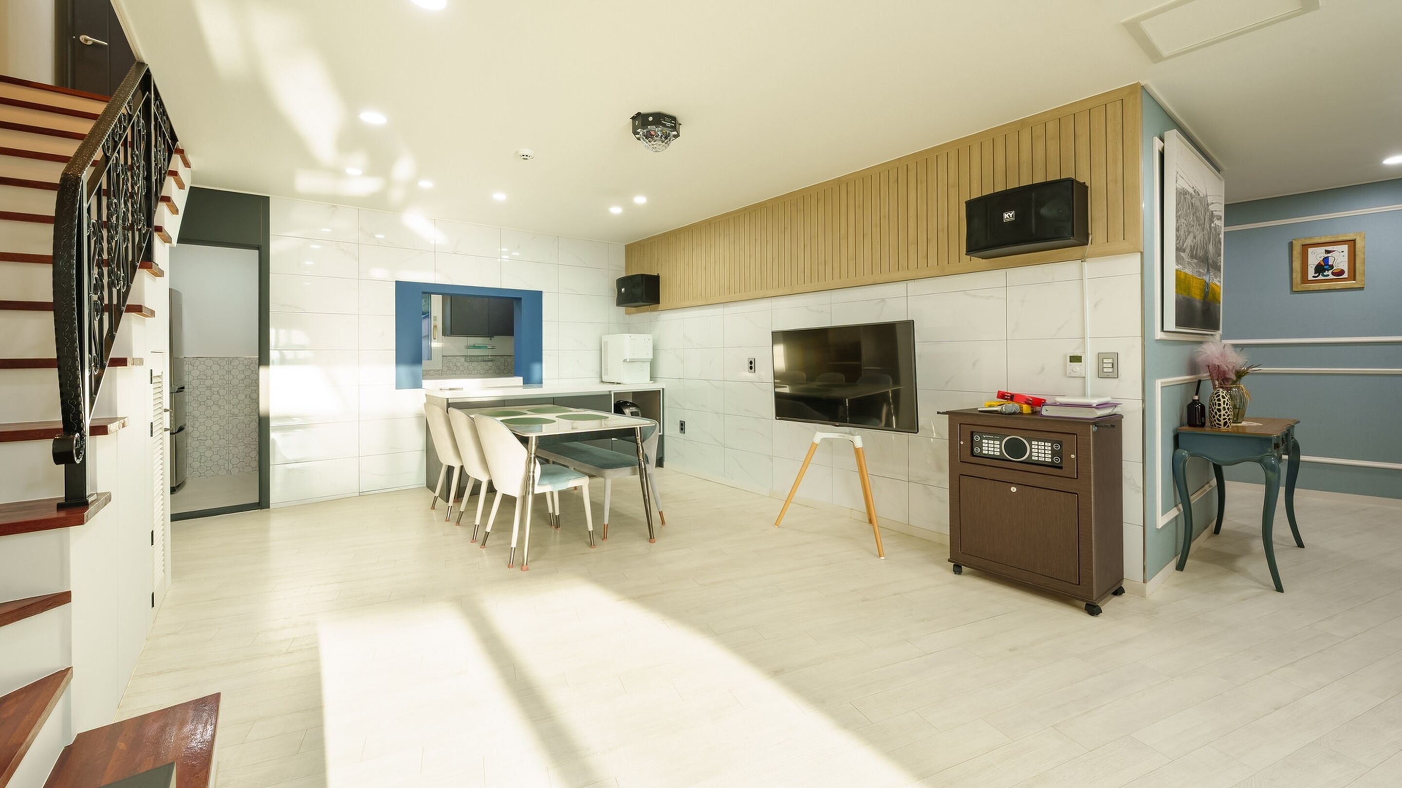 A modern kitchen with white cabinets, a dining area with a table and chairs, a built-in oven, and a microwave.
