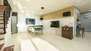 A modern kitchen with white cabinets, a dining area with a table and chairs, a built-in oven, and a microwave.