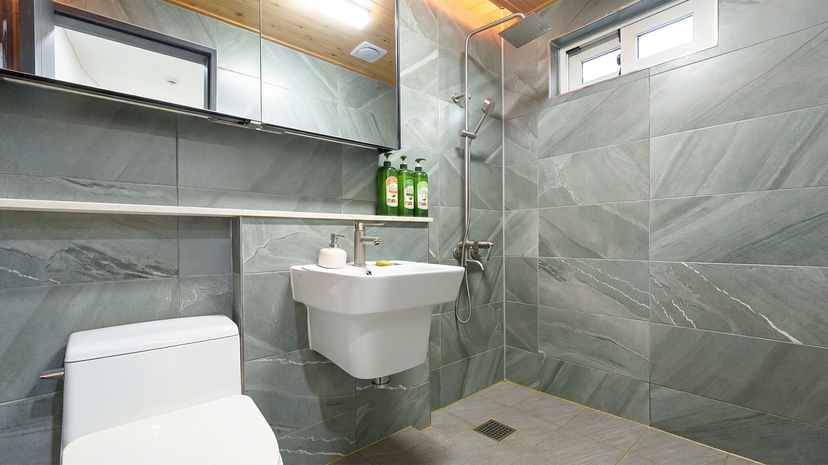 A modern bathroom with a white toilet, a pedestal sink, and a shower area.