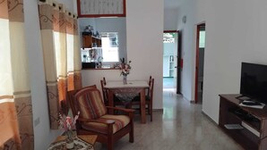 Un soggiorno con zona pranzo, un mobile TV e una cucina sullo sfondo.
