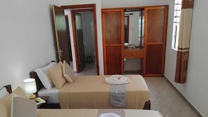 Una camera d'albergo con due letti, una scrivania e un armadio.