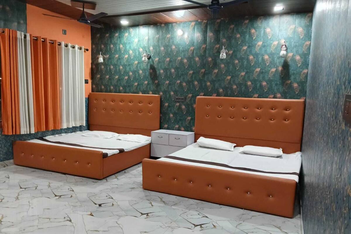 Una habitación con dos camas, una mesita y una lámpara fijada a la pared.