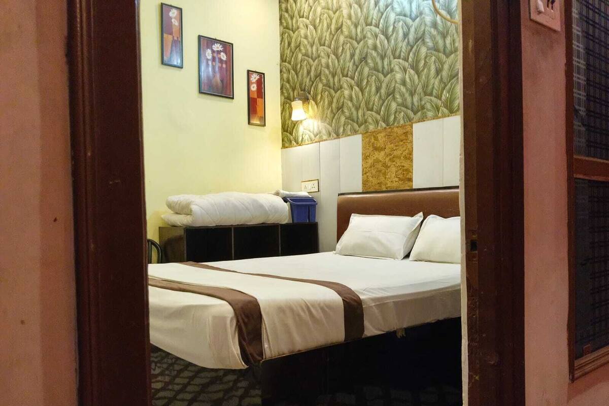 Una habitación de hotel con una cama, una mesita de noche y un papel tapiz con motivos de hojas.