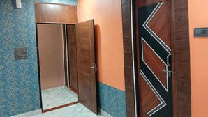 A room with a wooden door with a geometric design, a blue patterned wall, and a marble floor. - Fauzi Rasoi & Guest House (Faizabad)